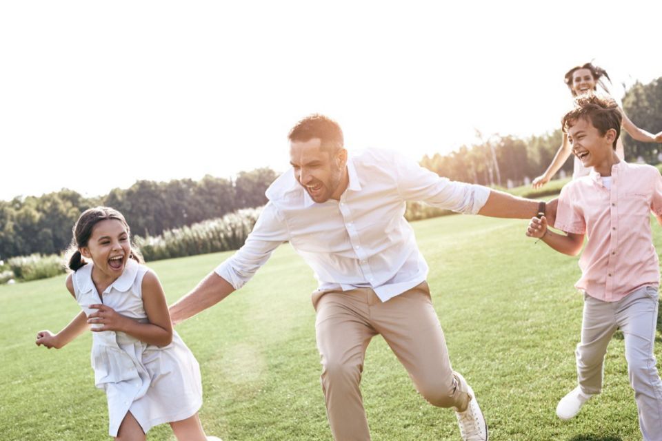 a father running through field with son and daughter next to him and his wife running behind them