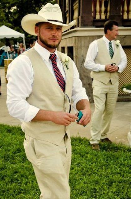 a cowboy-inspired groom's look with neutral pants and a waistcoat, a white shirt, a burgundy tie and a white hat