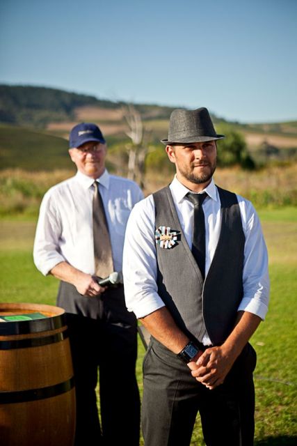 a rustic groom's look with black pants, a black waistcoat, a black tie, a black hat and a white shirt