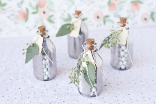 mercury glass bottles with candies and soem fresh greenery attached to them