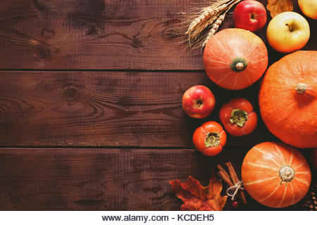 Thanksgiving background: pumpkins, apples, wheat, maple leaves, cones and spices on brown wooden background. Seasonal - Stock Image