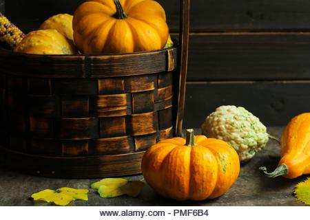 Autumn fall Thanksgiving background or Frame with pumpkins maple leaves acorn nuts on rust icbasket, copy space - Stock Image