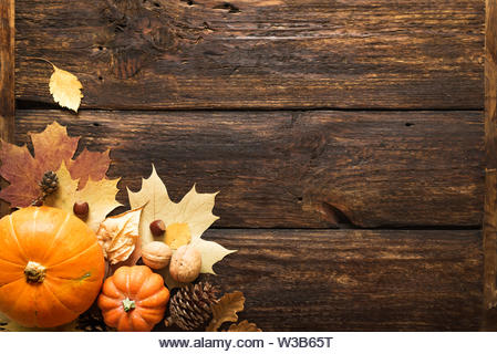 Thanksgiving or Autumnal holiday background, top view, copy space. Autumnal holiday composition with pumpkins, nuts, yellow leaves. - Stock Image