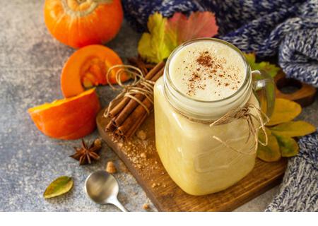 Autumn pumpkin spiced latte or coffee in glass with organic ingredients on a light stone countertop. - Stock Image