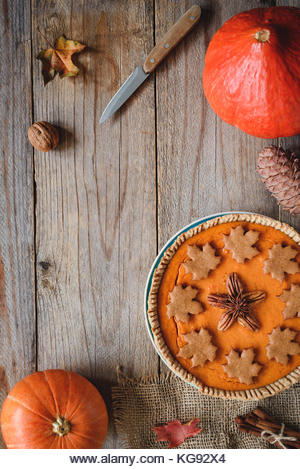 Pumpkin pie, pumpkins, knife and maple leaf on old wooden table. Copy space for text. Fall comfort food, Thanksgiving - Stock Image