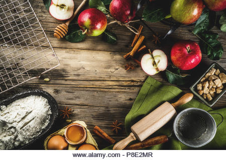 Autumn cooking background, Apple pie baking concept, fresh red apples, sweet spices, sugar, flour, rolling pin, eggs, baking utensils, wooden backgrou - Stock Image