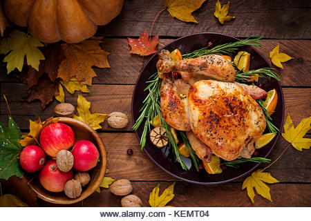 Roasted turkey garnished with cranberries on a rustic style table decorated with pumpkins, orange, apples and autumn - Stock Image