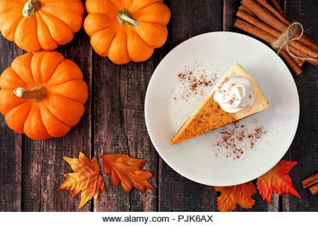 Slice of pumpkin cheesecake with whipped cream, top view on a rustic wooden background - Stock Image