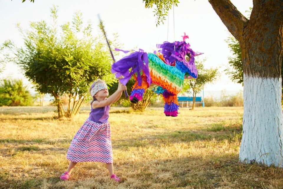 girl with blindfold hitting a multicolored pi&#xf1;ata