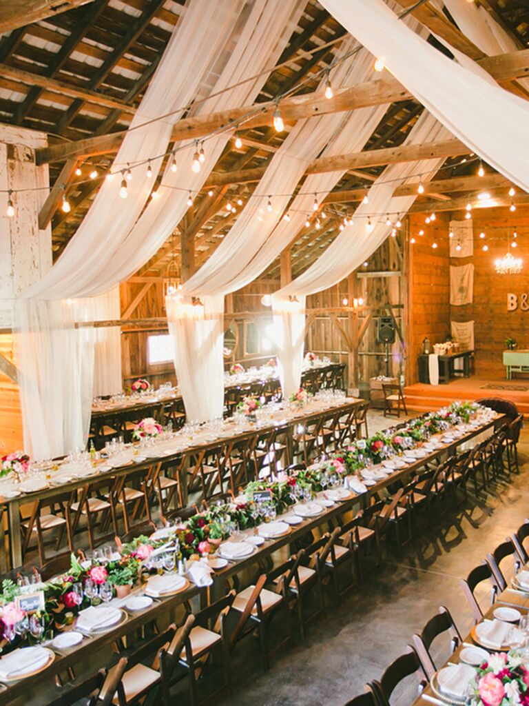 Rustic barn reception space with draped white fabric decor