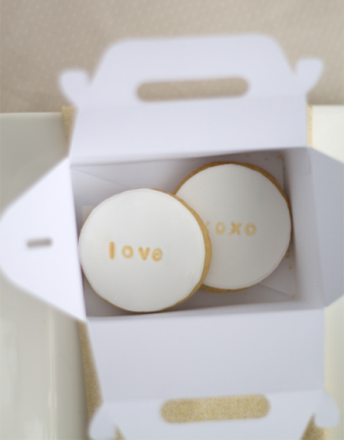 a box with two glazed cookies with LOVE and XOXO are a cool modern idea for a rehearsal dinner