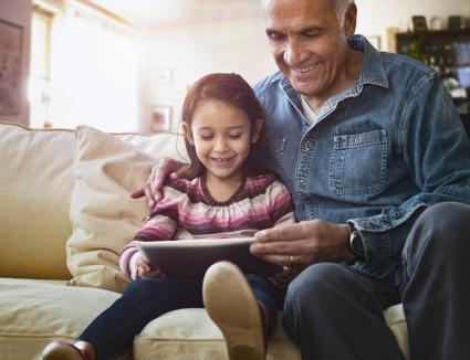 Grandfather and granddaughter on sofa using tablet
