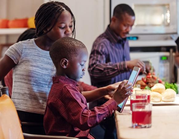 Boy playing game on tablet and dad preparing thanksgiving dinner