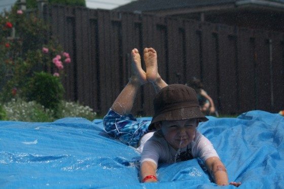 preschool boy sliding head first on homemade water slide