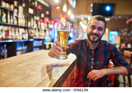 Happy Young Man Cheering at Bar Counter - Stock Image