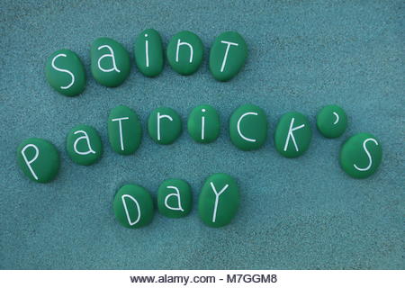 Happy Saint Patrick's day with green painted stones over green sand - Stock Image