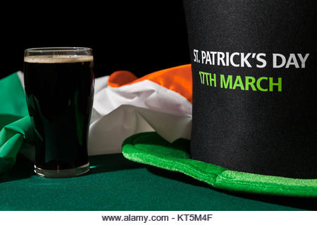Closeup of St Patrick day with a pint of black beer, hat and irish flag - Stock Image