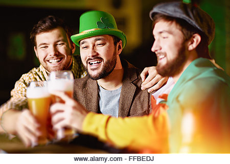 Happy men with beer spending St. Patrick day in Irish pub - Stock Image