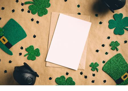 St Patrick's Day banner design. Blank paper card, Irish elf hats, pots of gold, shamrock clover leaves on kraft paper background. Happy Saint Patrick’ - Stock Image