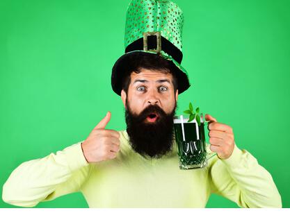 Saint Patricks Day. Happy bearded man with glass of beer shows sign good. Clover in mug of beer. Ireland tradition. - Stock Image