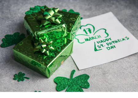 Decorative clover leaves, green gifts box, coins on stone background, flat lay. St. Patrick's Day celebration. Card Happy St. Patrick's Day - Stock Image