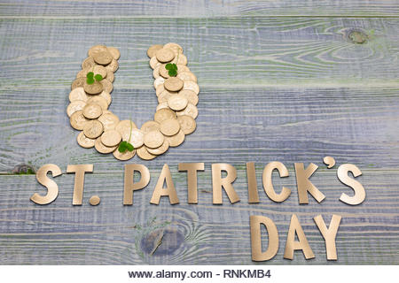 symbol of good luck horseshoe, lined with British gold coins, clover, inscription in golden letters - St. Patricks day - Stock Image