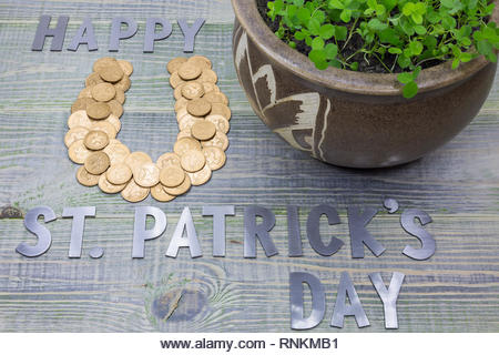 symbol of good luck horseshoe, lined with British gold coins, pot of clover, inscription in letters - St. Patricks day - Stock Image
