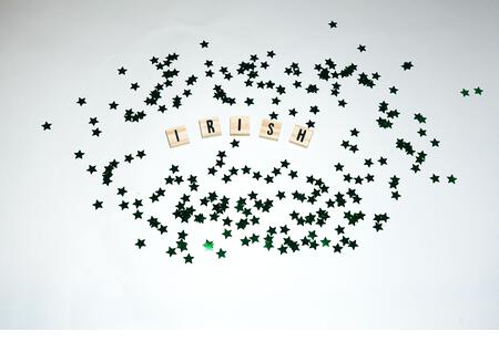 Happy St. Patricks Day festive wooden letters spelling irish and green stars flatlay on white background. - Stock Image