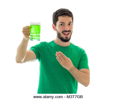 Handsome man is holding and pointing a big mug. Young man wearing green clothes on white background, related to - Stock Image