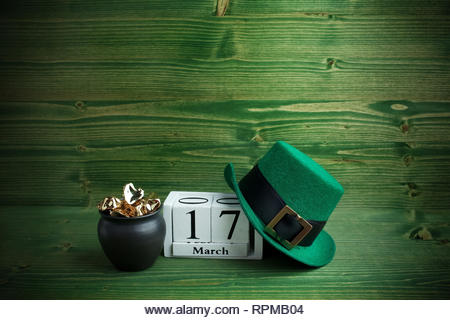 white block calendar for St Patrick's Day, March 17, with Leprechaun hat and pot of gold, on green wooden background. - Stock Image