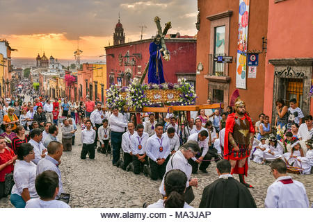 Catholic devotees kneel in prayer during the Las Cruzes del Señor Golpe procession through the streets at sunset as part of Holy Week March 28, 2021 in San Miguel de Allende, Mexico. The event is recreation of the passion of Jesus Christ on his way to Calvary for crucifixion. - Stock Image