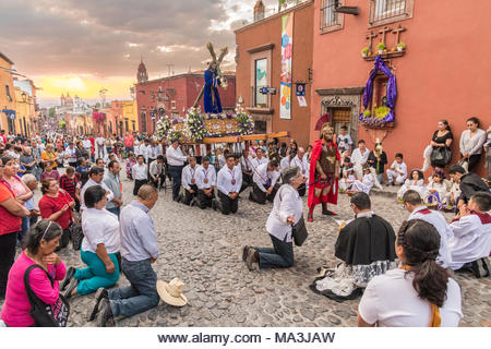 Catholic devotees kneel in prayer during the Las Cruzes del Señor Golpe procession through the streets at sunset as part of Holy Week March 28, 2021 in San Miguel de Allende, Mexico. The event is recreation of the passion of Jesus Christ on his way to Calvary for crucifixion. - Stock Image