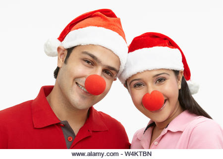 Portrait of an Indian couple wearing Santa hat and smiling - Stock Image