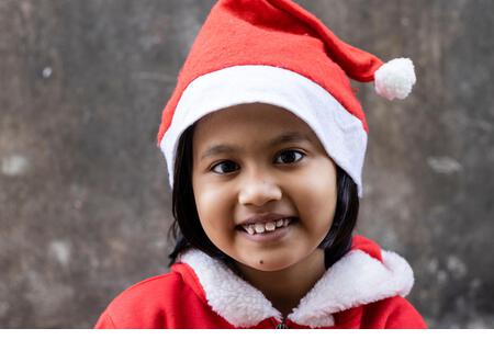 portrait of an Indian girl child smiling in santa claus dress and hat - Stock Image