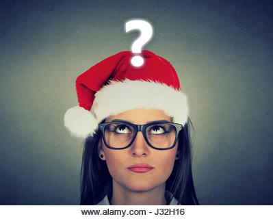 Young woman in santa claus hat with question mark - Stock Image