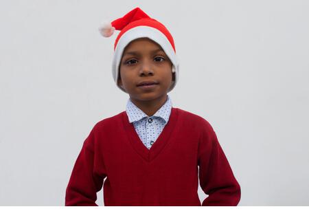 Young boy smiling and wearing Santa Claus hat, during christmas - Stock Image