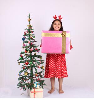 Cute little Indian girl holding Christmas gift. - Stock Image