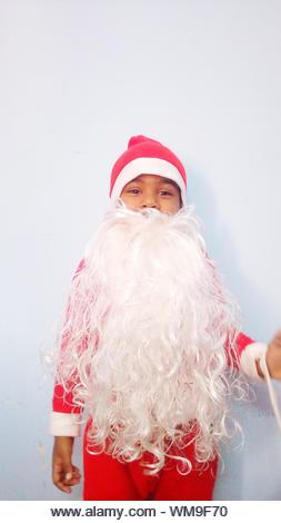 Portrait Of Boy Wearing Santa Claus Costume Against White Background - Stock Image