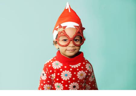 Sweet little girl wearing christmas glasses in santa hat - Stock Image