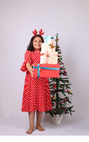 Cute little Indian girl holding Christmas gift. - Stock Image