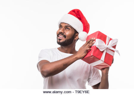 Happy indian man wearing santa hat and holding gift box isolated on white background - Stock Image