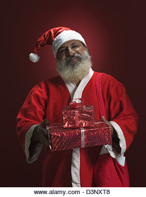 Man dressed as Santa Claus holding presents - Stock Image