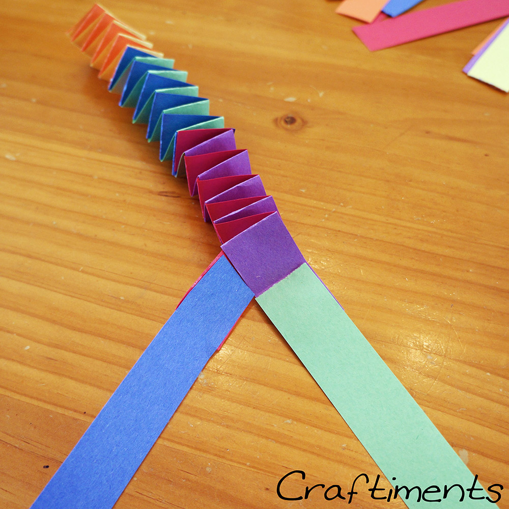 Adding more strips to folded paper garland.