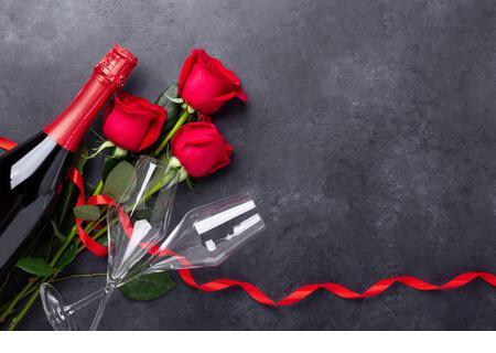 Valentines day greeting card. Red roses, champagne, glasses on stone background. Top view- Image - Stock Image