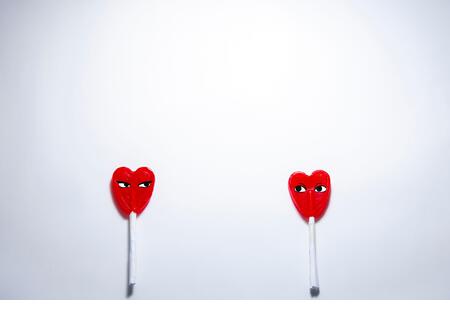 Cenital plane. Two heart-shaped lollipops separated from each other. Valentine's Day concept during the Covid-19 pandemic and safety distance - Stock Image