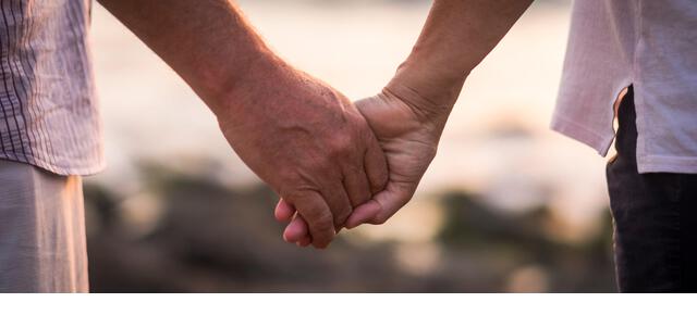 valentine's day love over time concept with hands of man and woman mature old people aged taking together each other with defocused background - romance and romantic picture for retired life - Stock Image