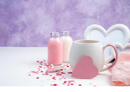 Romantic background with a pink heart on a coffee mug, white frame, milk and hearts on a white and purple background. - Stock Image
