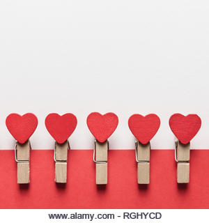 Wooden clothes pin with red textile hearts. Valentines day background, creative texture and love concept - Stock Image