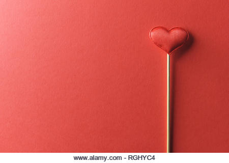Red textile heart on wooden stick closeup. Valentines day background, creative texture and love concept - Stock Image