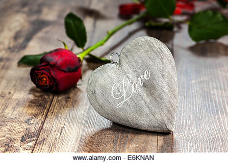Valentine's day symbol. Heart on a wooden background with red rose. - Stock Image